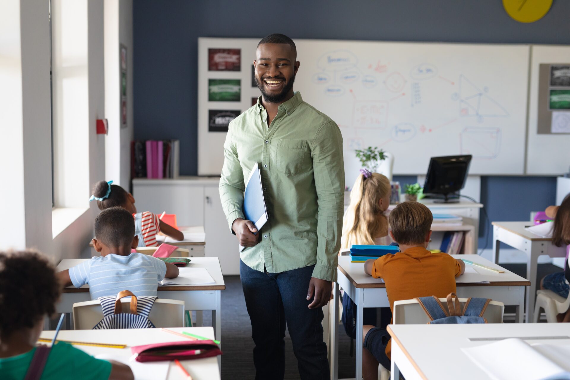 Smiling African American Male Teacher Standing with Laptop