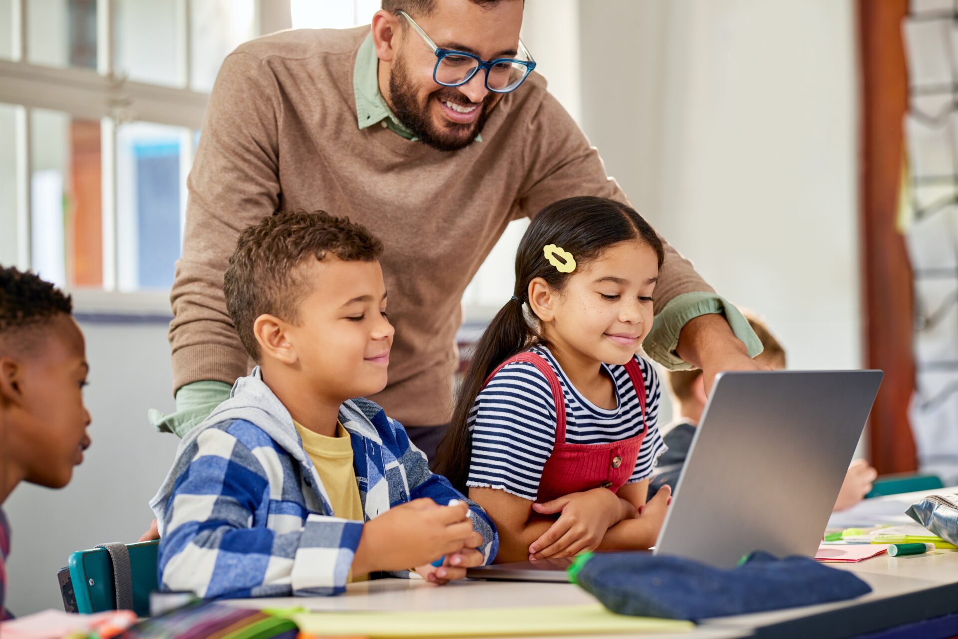 Elementary Teacher Working with Students on Laptop